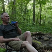 Mark Neese of True North Counseling sitting in a camping chair in the woods.
