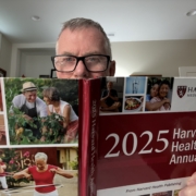 Mark Neese poses with a copy of the 2025 Harvard Health Annual for the Season 12 teaser of the Healthy Aging Series on the True North Counseling blog.