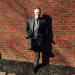 Mark Neese, owner of True North Counseling, poses for a photo against a brick wall.