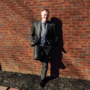 Mark Neese, owner of True North Counseling, poses for a photo against a brick wall.